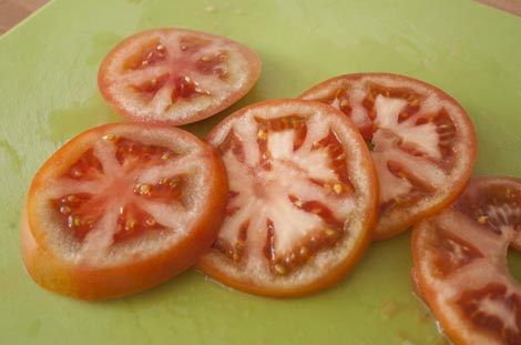 Cortar el tomate para hacer el milhojas con berenjenas y mozzarella