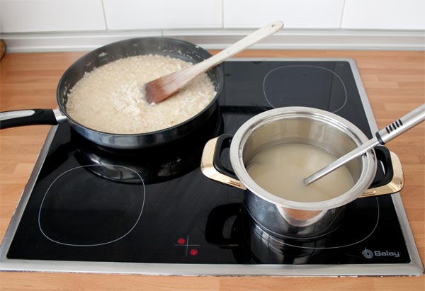 Agregar el caldo caliente poco a poco al risotto y remover