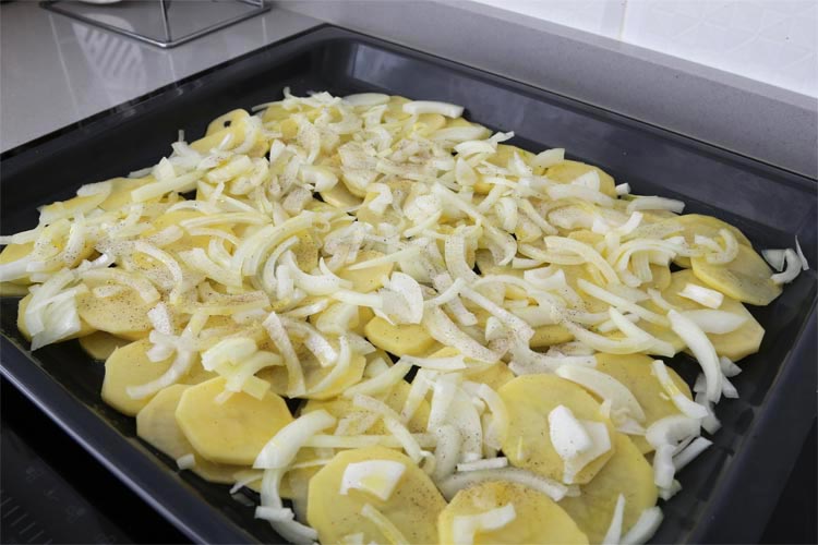 Colocar las patatas y la cebolla sobre la bandeja del horno