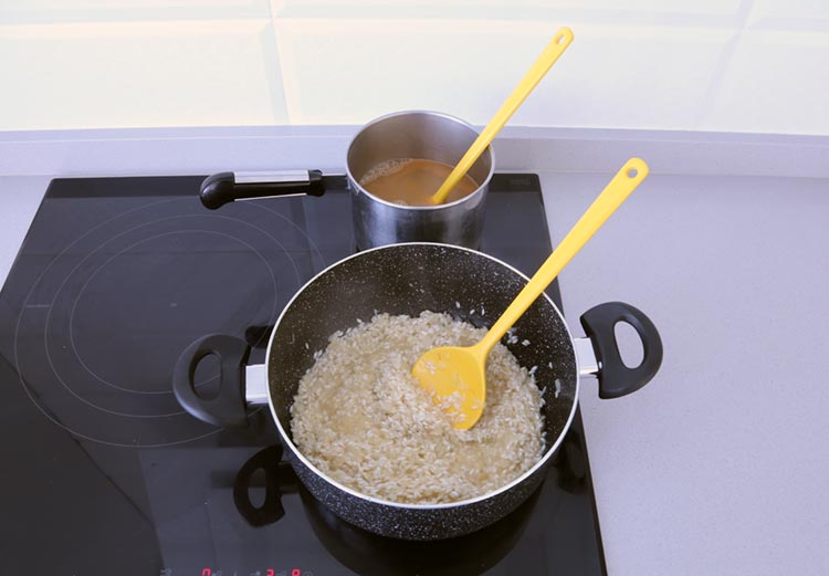 Añadir el caldo caliente poco a poco mientras se remueve el arroz