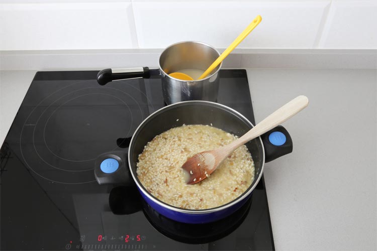 Añadir el caldo poco a poco y remover el risotto