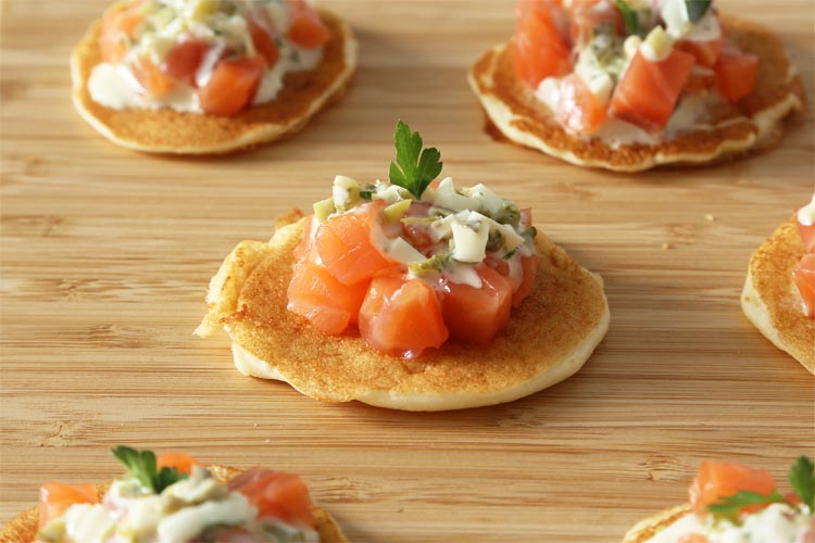 Decorar los blinis con la salsa tártara y una hojita de perejil