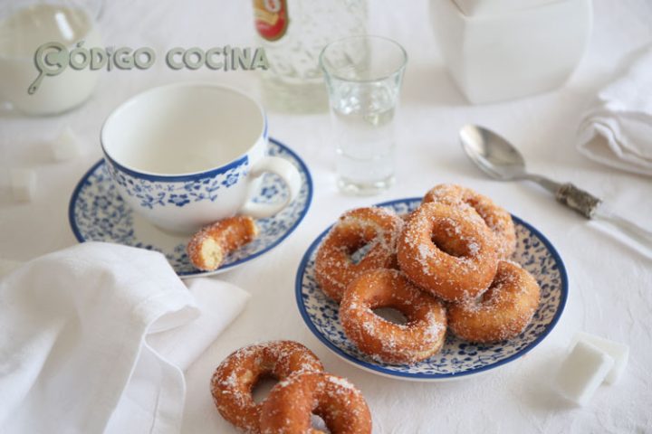 Rosquillas de anís caseras rebozadas con azúcar sobre un plato de postre.