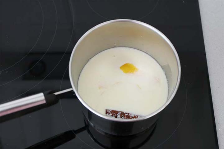 Cazo de leche infusionando con una rama de canela y piel de limón