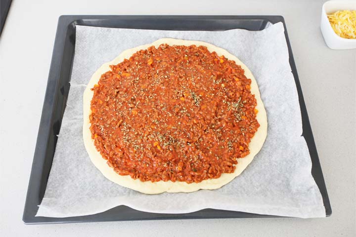 Colocar la salsa boloñesa sobre la masa de la pizza