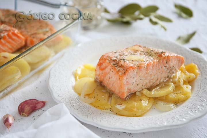 Salmón al horno sobre una cama de patatas y cebolla decorado con eneldo