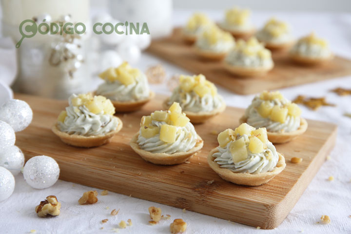 Tartaletas de queso roquefort con nueces y manzanas sobre una tabla de madera.