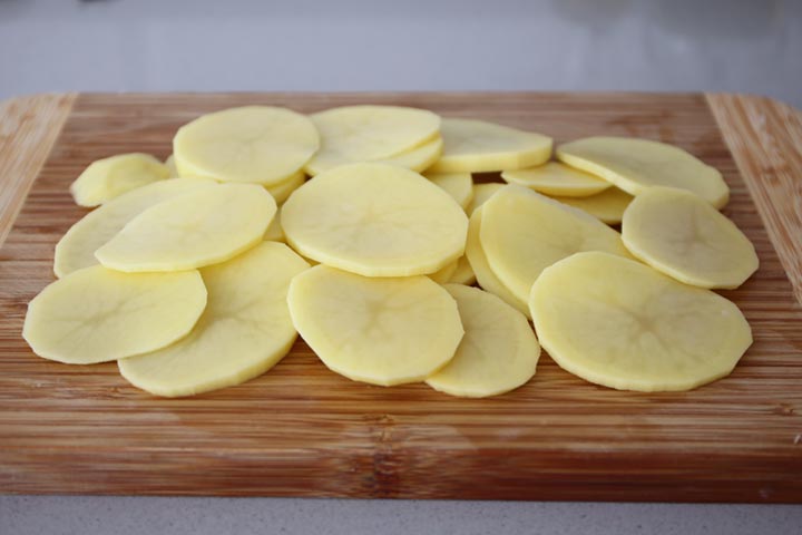 Patata cortada el rodajas finas sobre una tabla de madera