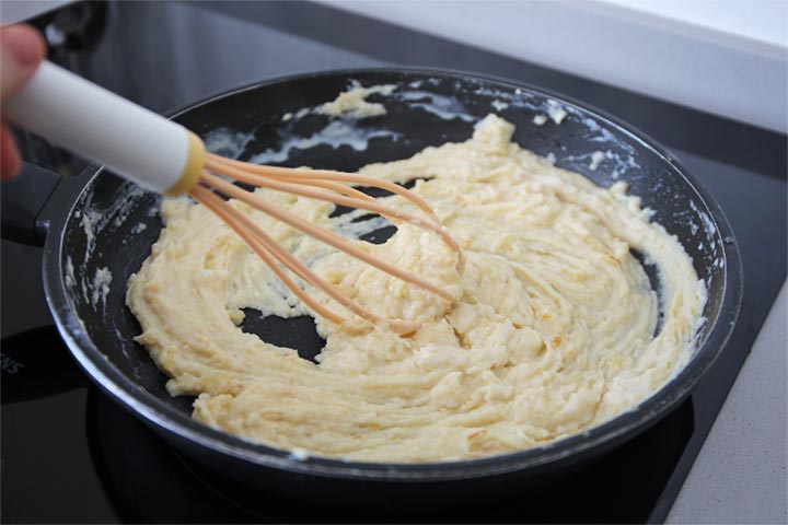 Bechamel dentro de una sartén siendo removida para quitar los grumos