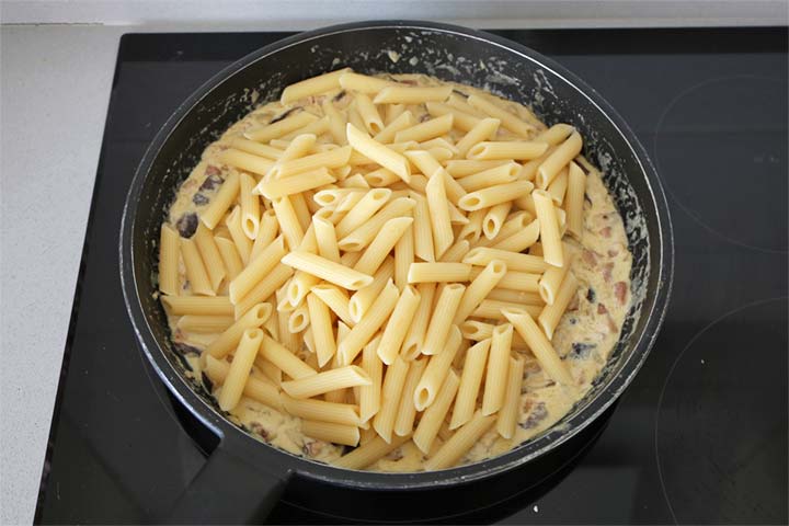 Pasta cocida recién incorporada a la salsa de nata, setas y jamón 