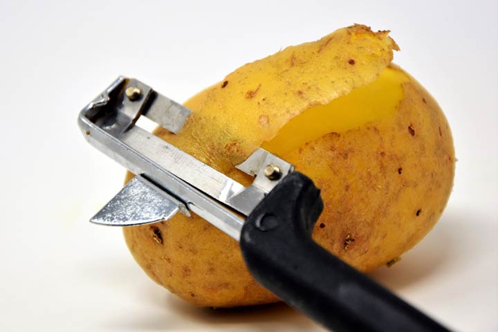 Pelador de verduras retirando la piel de una patata