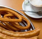 Bandeja con churros y porras junto a una taza de café