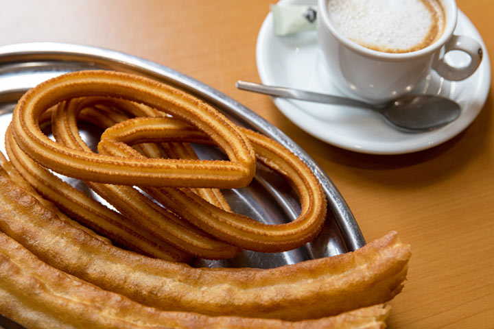 Bandeja con churros y porras junto a una taza de café