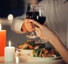 Una pareja brindando con dos copas de vino en cena romántica