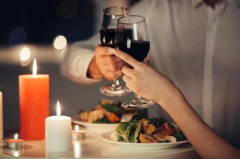 Una pareja brindando con dos copas de vino en cena romántica